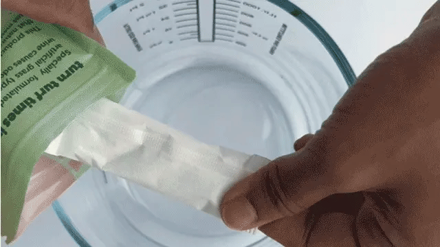 Showing how Turfy pet stain eliminator sachet fully dissolves to make artificial grass cleaning solution